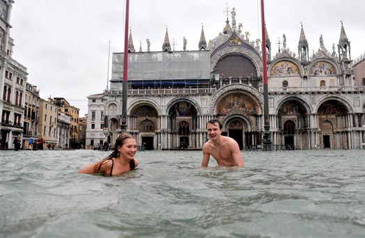 A man and woman swim in flooded Piazza San Marco (St. Mark's Square) in Venice, Italy